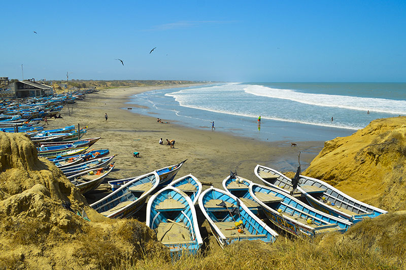 A picturesque scene of blue boats on the beach of Playas, Ecuador